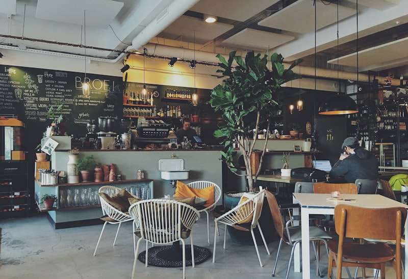 Ruang utama dengan kursi rotan, pohon ara, dan bar kopi di belakang