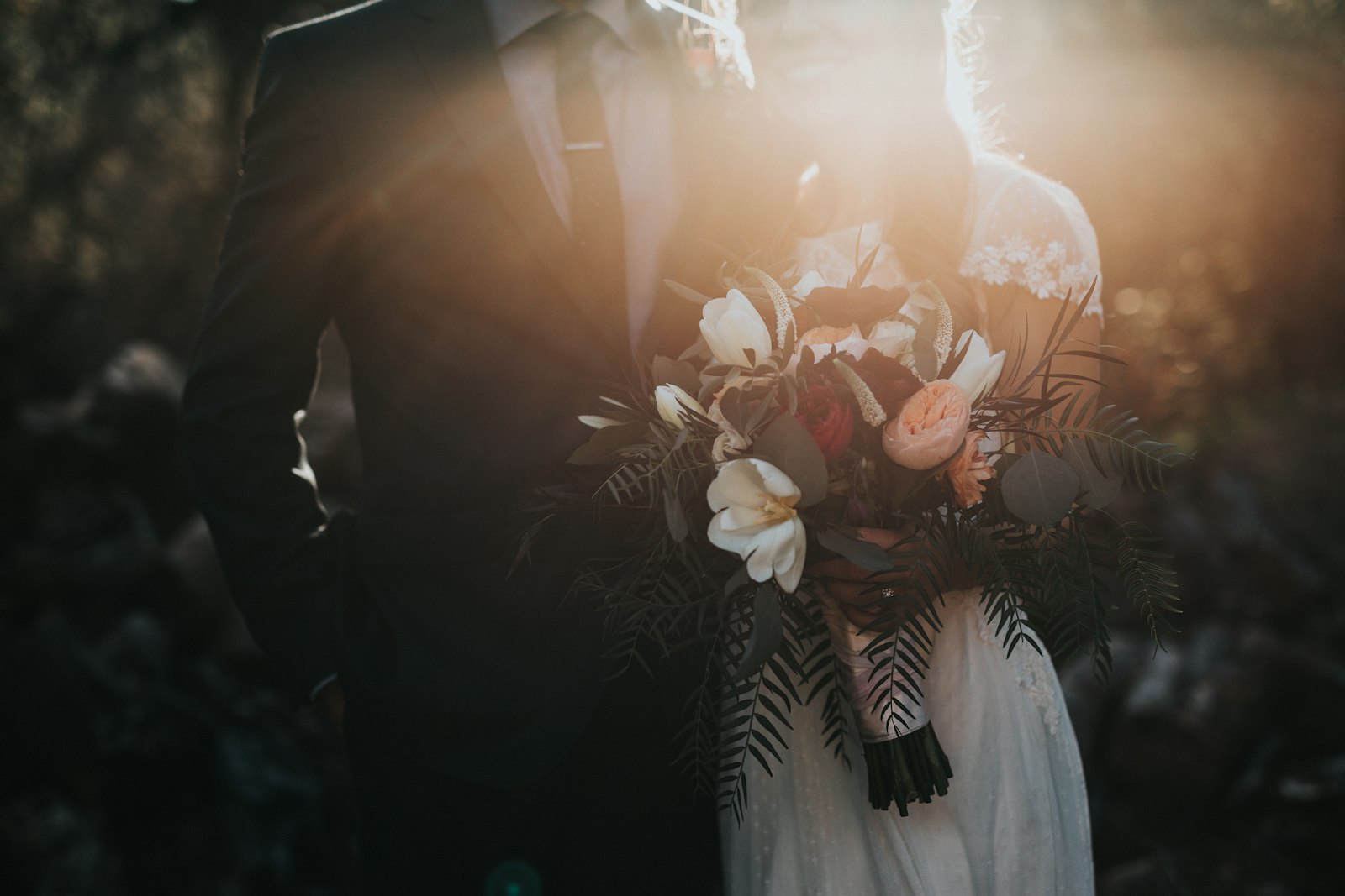 Pasangan pengantin berdiri romantis di luar ruangan saat senja