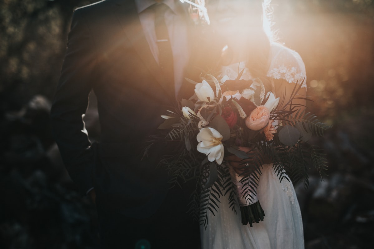 Pasangan pengantin berdiri romantis di taman saat senja